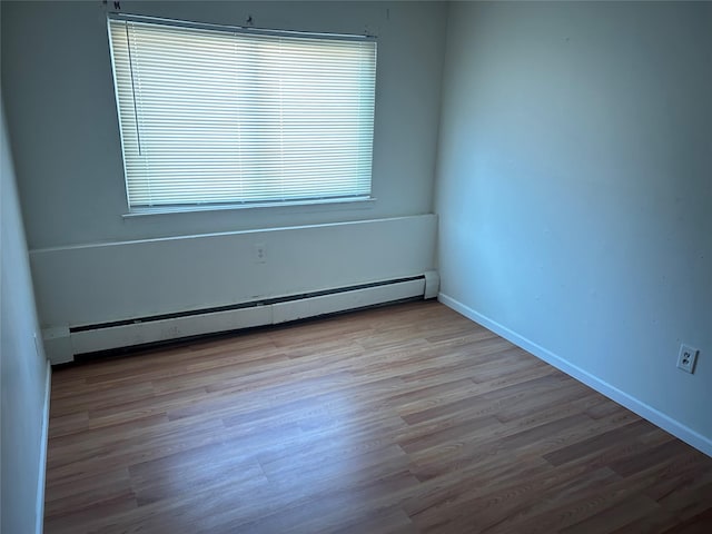 spare room featuring baseboard heating and light wood-type flooring