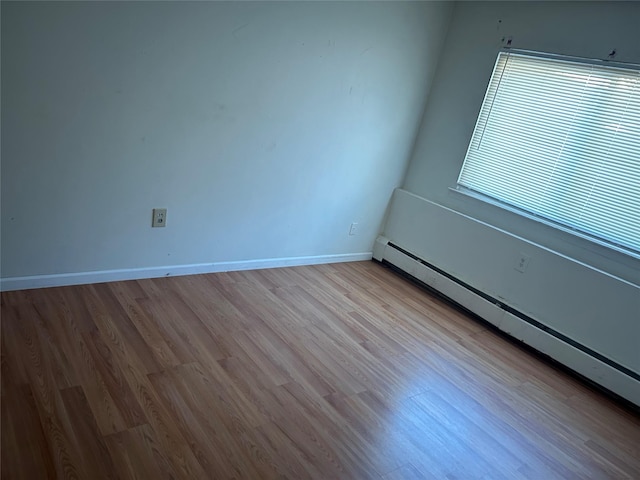 empty room with baseboard heating and light hardwood / wood-style flooring