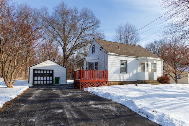 snow covered property featuring a garage and an outdoor structure