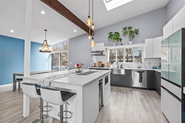 kitchen featuring white cabinets, a kitchen island, hanging light fixtures, and appliances with stainless steel finishes