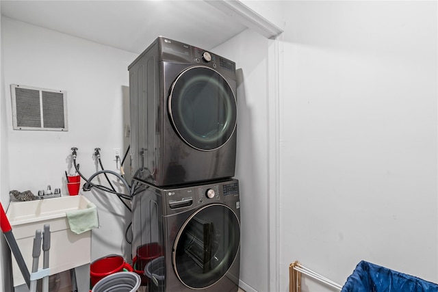 clothes washing area featuring stacked washing maching and dryer