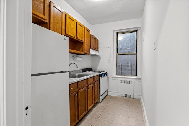 kitchen featuring radiator heating unit, white appliances, and sink