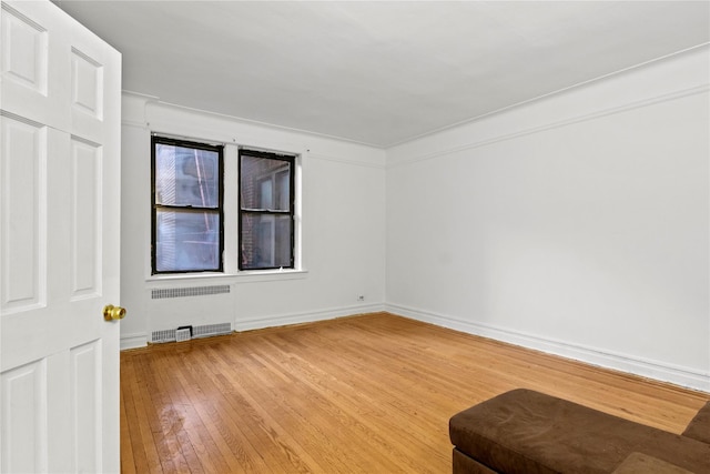 empty room featuring radiator heating unit and wood-type flooring