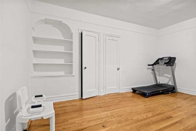 exercise room with hardwood / wood-style flooring and built in features