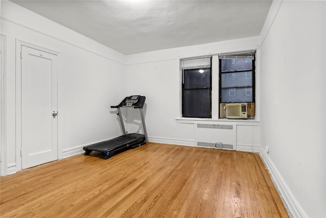 exercise room featuring radiator heating unit, cooling unit, and hardwood / wood-style flooring