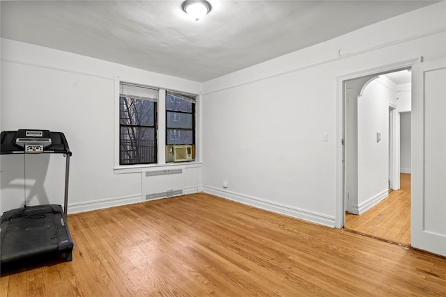 exercise room with hardwood / wood-style floors, radiator heating unit, and cooling unit