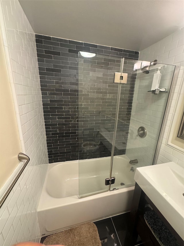 bathroom featuring combined bath / shower with glass door and tile walls