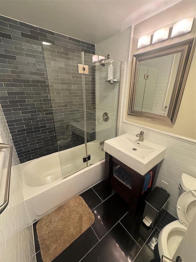 full bathroom featuring bath / shower combo with glass door, vanity, tile walls, tile patterned flooring, and toilet