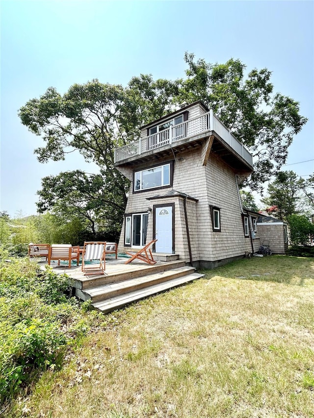 rear view of property with a lawn, a wooden deck, and a balcony