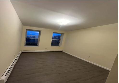 unfurnished room with dark hardwood / wood-style flooring and baseboard heating