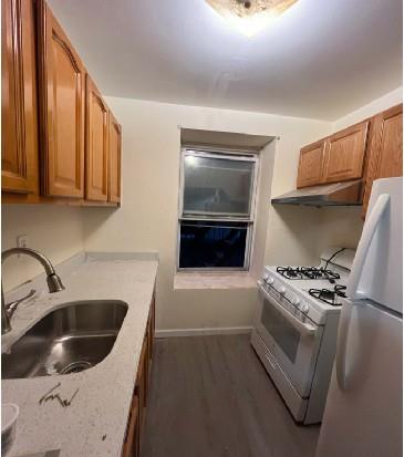 kitchen featuring dark hardwood / wood-style flooring, white appliances, and sink