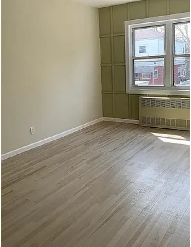 unfurnished room with light wood-type flooring and radiator heating unit