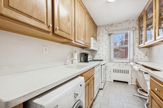 kitchen with white appliances, sink, light tile patterned floors, separate washer and dryer, and radiator heating unit