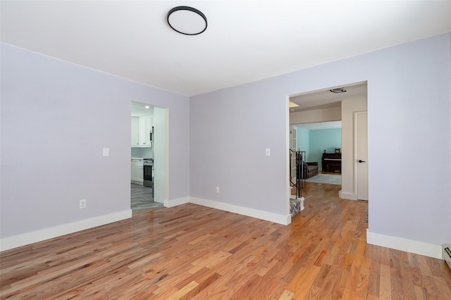 unfurnished room with light wood-type flooring and baseboard heating