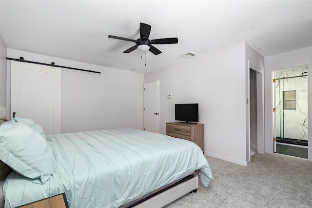 carpeted bedroom featuring a barn door, ceiling fan, and ensuite bathroom