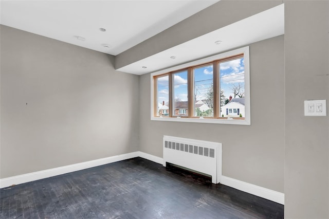 empty room with radiator heating unit and dark hardwood / wood-style floors