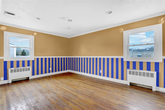 empty room with radiator, crown molding, and wood-type flooring