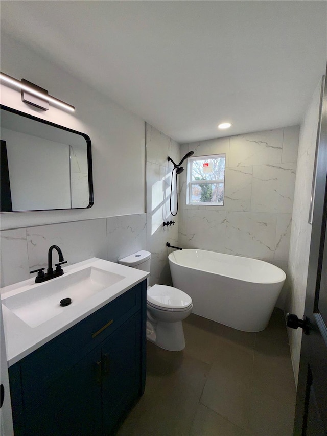 bathroom with vanity, tile patterned floors, toilet, a tub to relax in, and tile walls