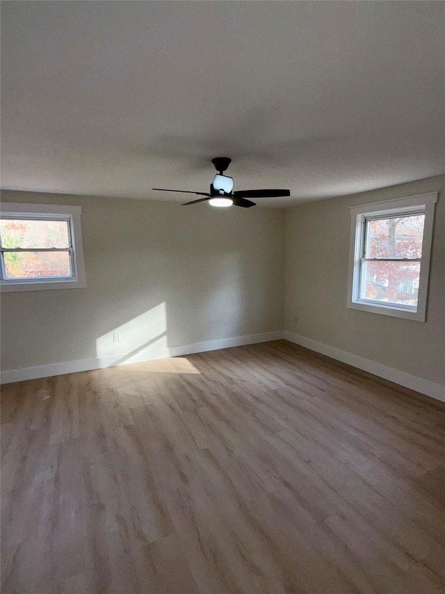 unfurnished room featuring ceiling fan, plenty of natural light, and light wood-type flooring