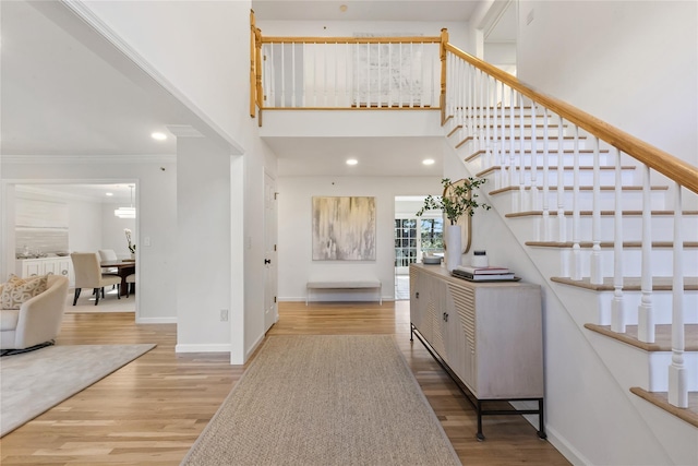 entryway featuring crown molding, a towering ceiling, and hardwood / wood-style flooring