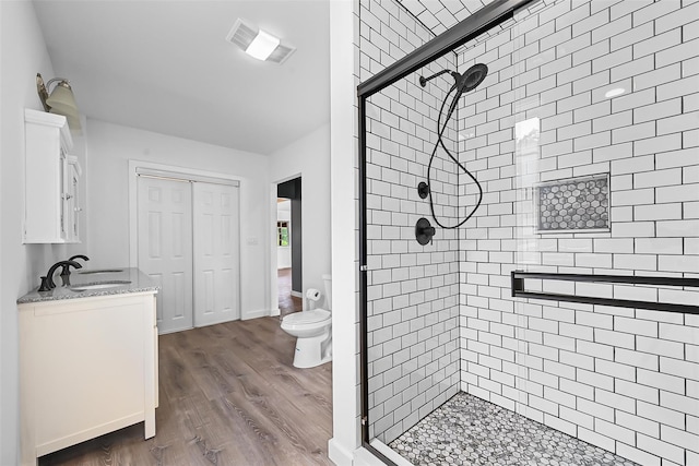 bathroom with a shower with door, vanity, wood-type flooring, and toilet