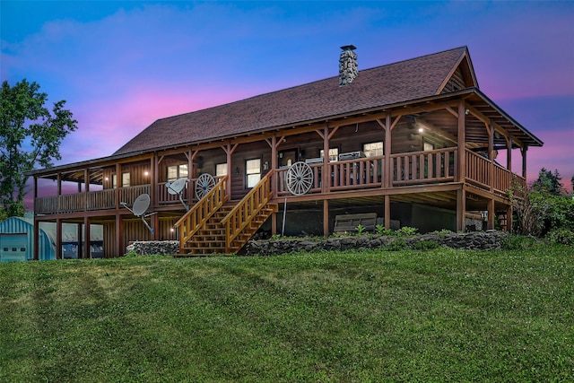 back house at dusk featuring a lawn and an outdoor structure