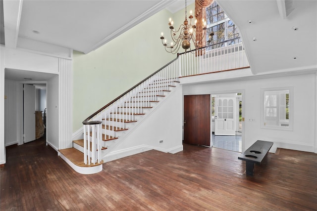 entryway with dark wood-type flooring, an inviting chandelier, and ornamental molding