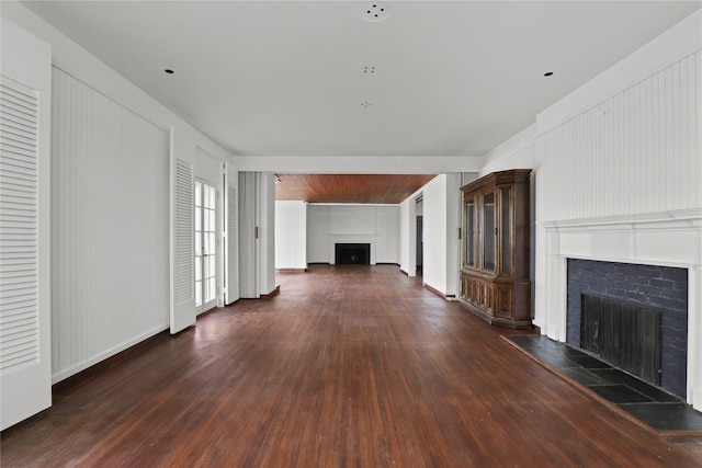 unfurnished living room with a tiled fireplace and dark hardwood / wood-style floors