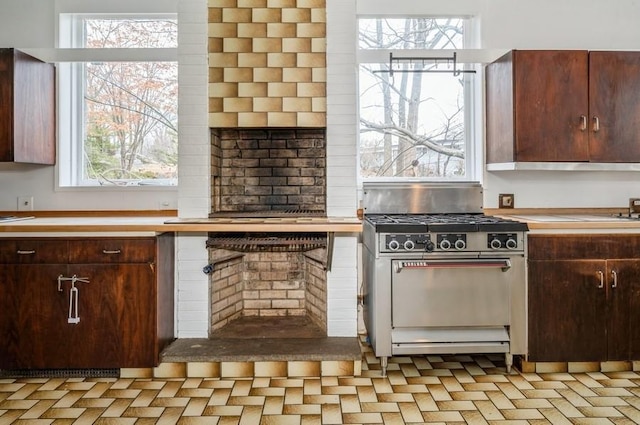 kitchen featuring a healthy amount of sunlight, dark brown cabinets, and gas range