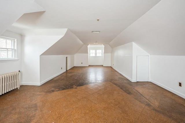 additional living space featuring radiator heating unit and vaulted ceiling