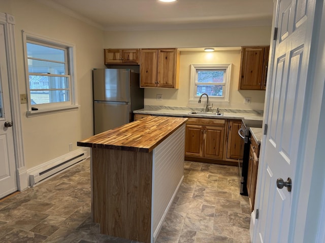 kitchen with butcher block counters, sink, baseboard heating, a kitchen island, and appliances with stainless steel finishes