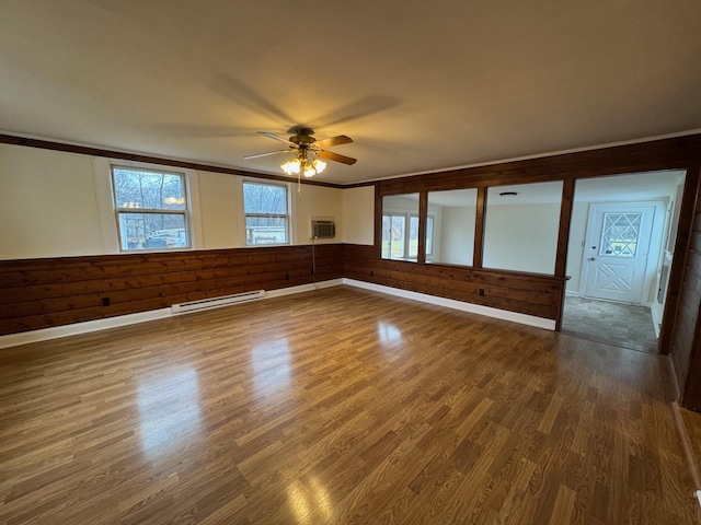 unfurnished room featuring ceiling fan, hardwood / wood-style flooring, and a baseboard heating unit