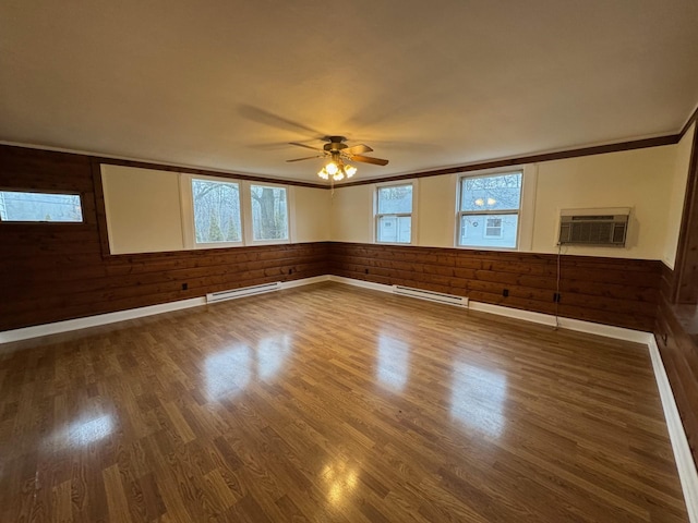 empty room with a baseboard radiator, a wall mounted AC, wood walls, and ceiling fan