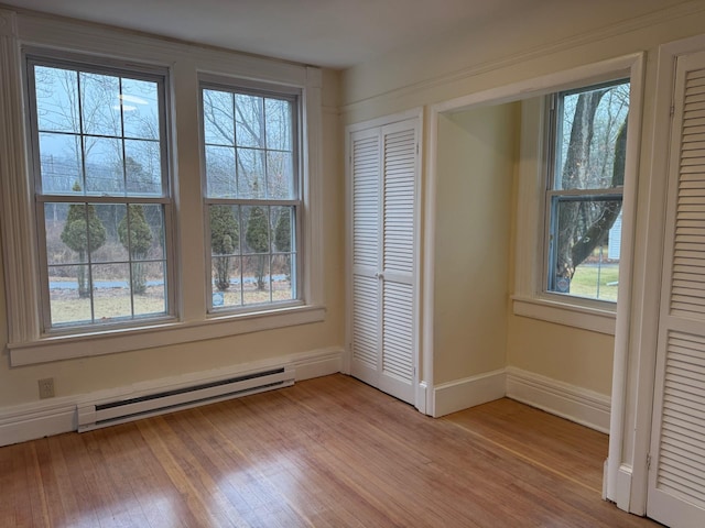 unfurnished bedroom with light hardwood / wood-style flooring, baseboard heating, and a closet