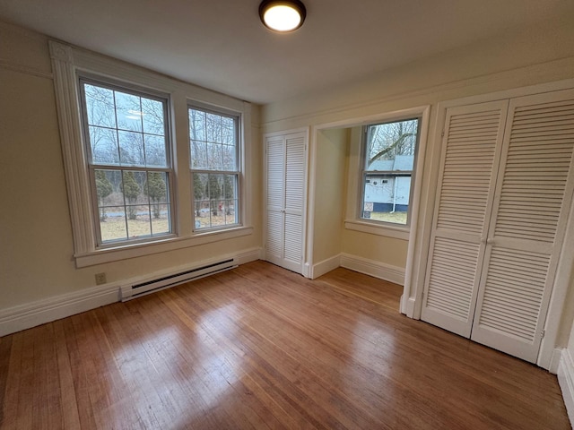 unfurnished bedroom with light hardwood / wood-style flooring and a baseboard radiator