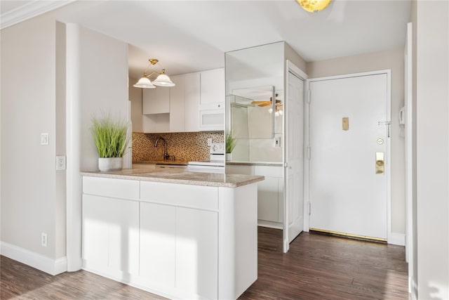 kitchen featuring kitchen peninsula, stove, backsplash, dark hardwood / wood-style flooring, and white cabinets