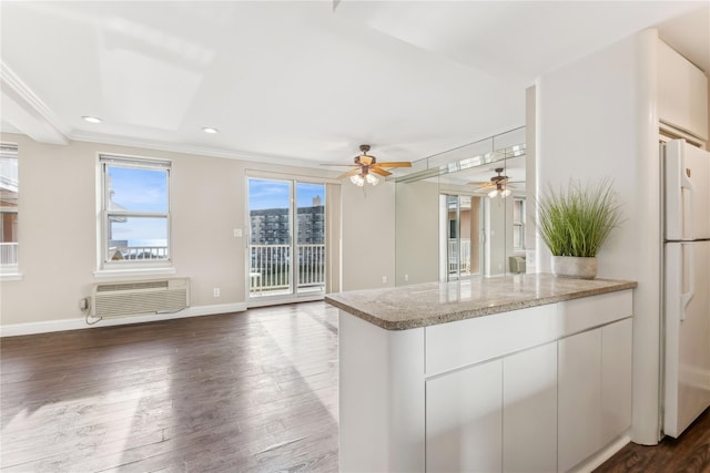 kitchen with a wall mounted air conditioner, white cabinets, white refrigerator, dark hardwood / wood-style floors, and light stone countertops