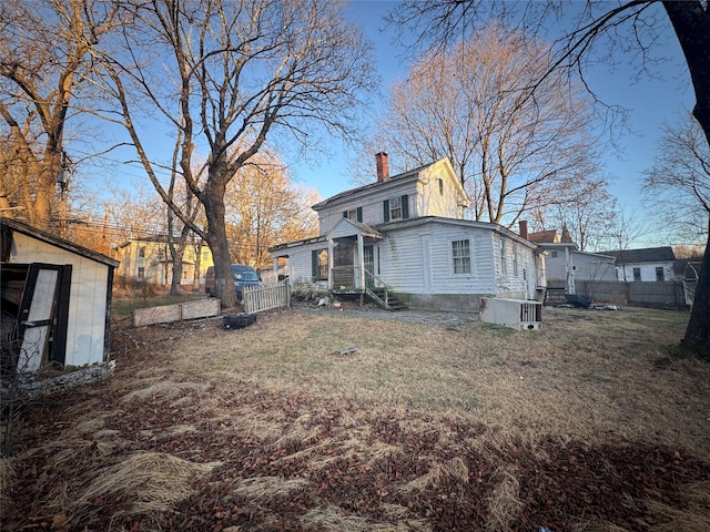 rear view of property featuring a storage unit and a lawn