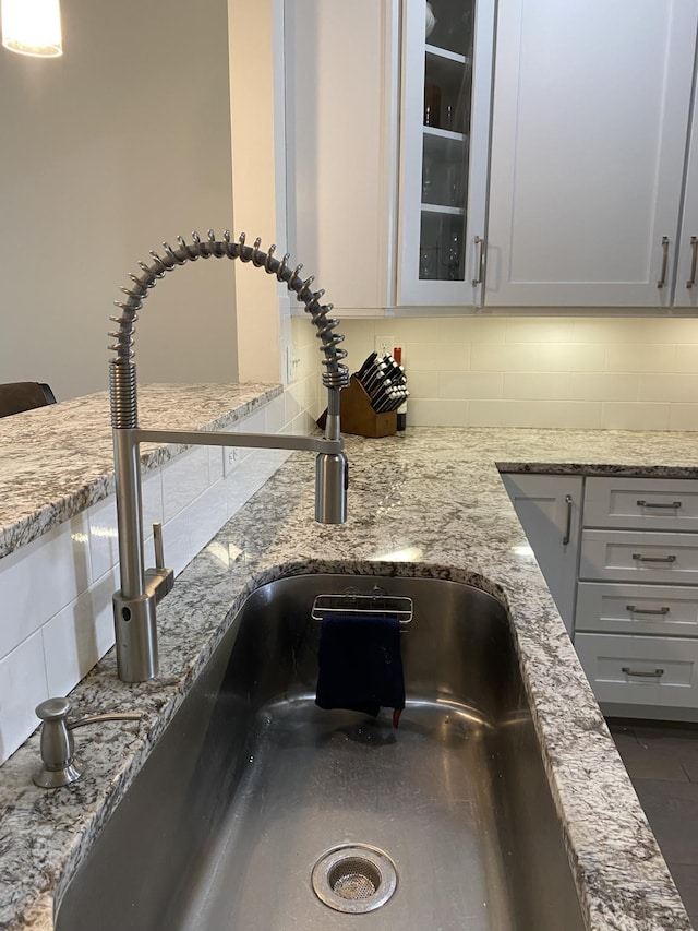 interior details with backsplash, light stone counters, and sink