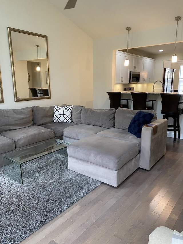 living room featuring hardwood / wood-style floors, lofted ceiling, and sink