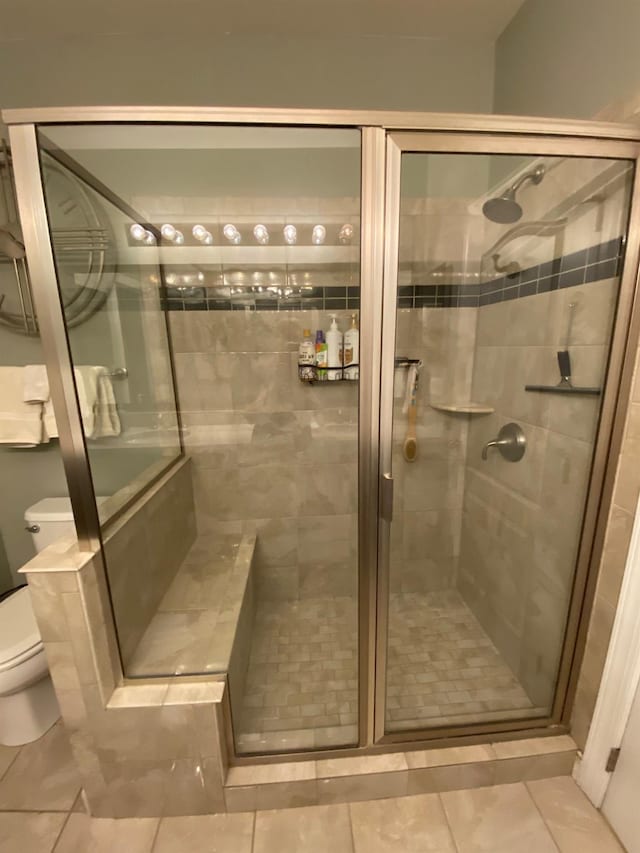 bathroom with tile patterned flooring, toilet, and a shower with door