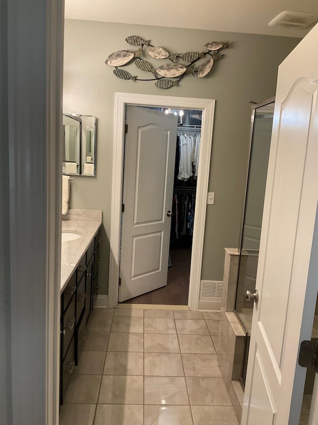 bathroom with tile patterned floors, a shower with door, and vanity