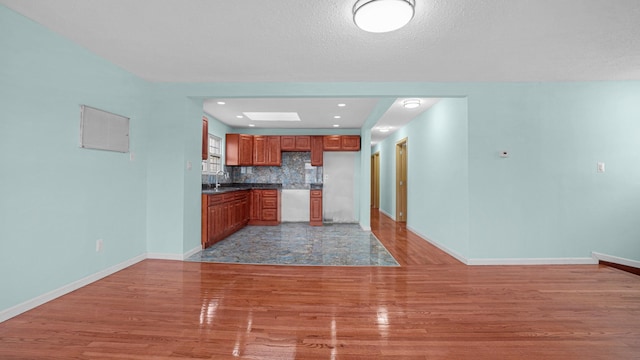 kitchen featuring wood-type flooring, a textured ceiling, backsplash, and sink