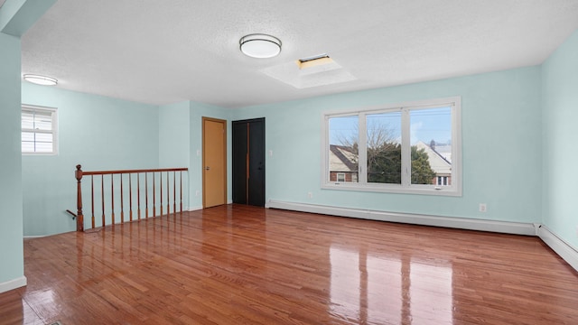 spare room with a skylight, light wood-type flooring, and a baseboard heating unit