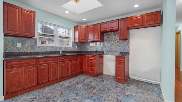 kitchen with tasteful backsplash, a skylight, sink, and dark stone counters