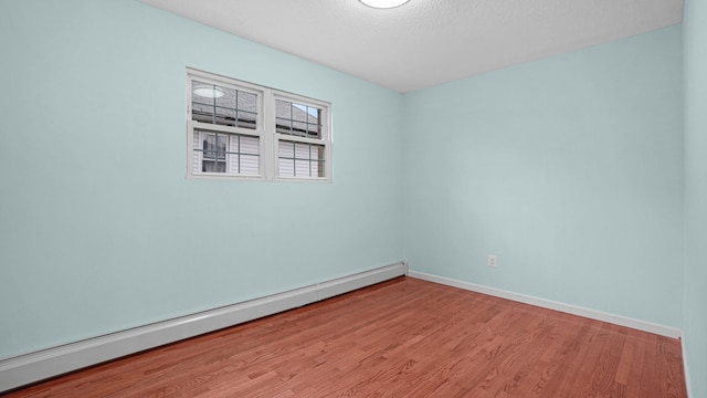 spare room featuring baseboard heating and hardwood / wood-style floors