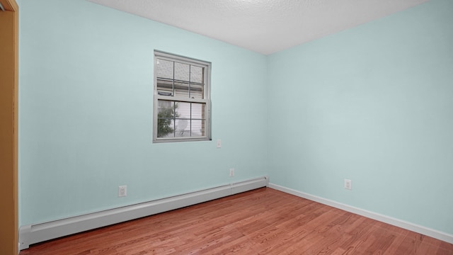 spare room with light hardwood / wood-style floors, a textured ceiling, and a baseboard heating unit