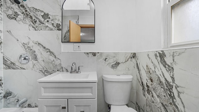 bathroom featuring vanity, toilet, and tile walls