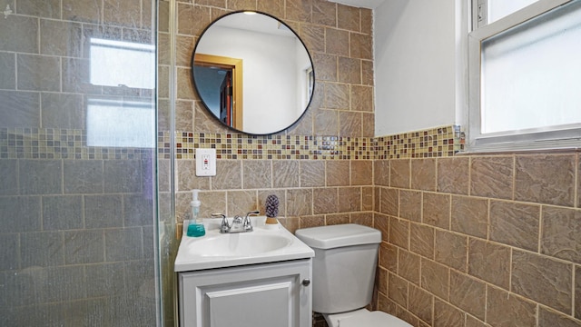 bathroom with vanity, toilet, and tile walls