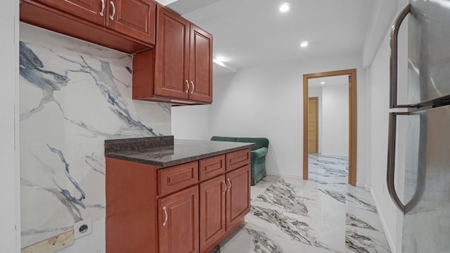 kitchen with stainless steel fridge and dark stone countertops